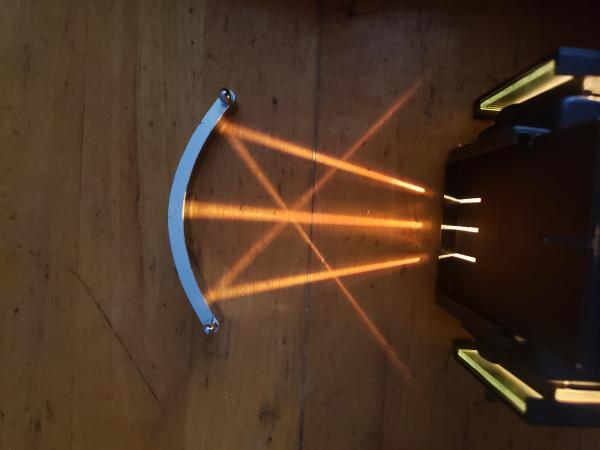 three rays of light converging after being reflected off a curved mirror