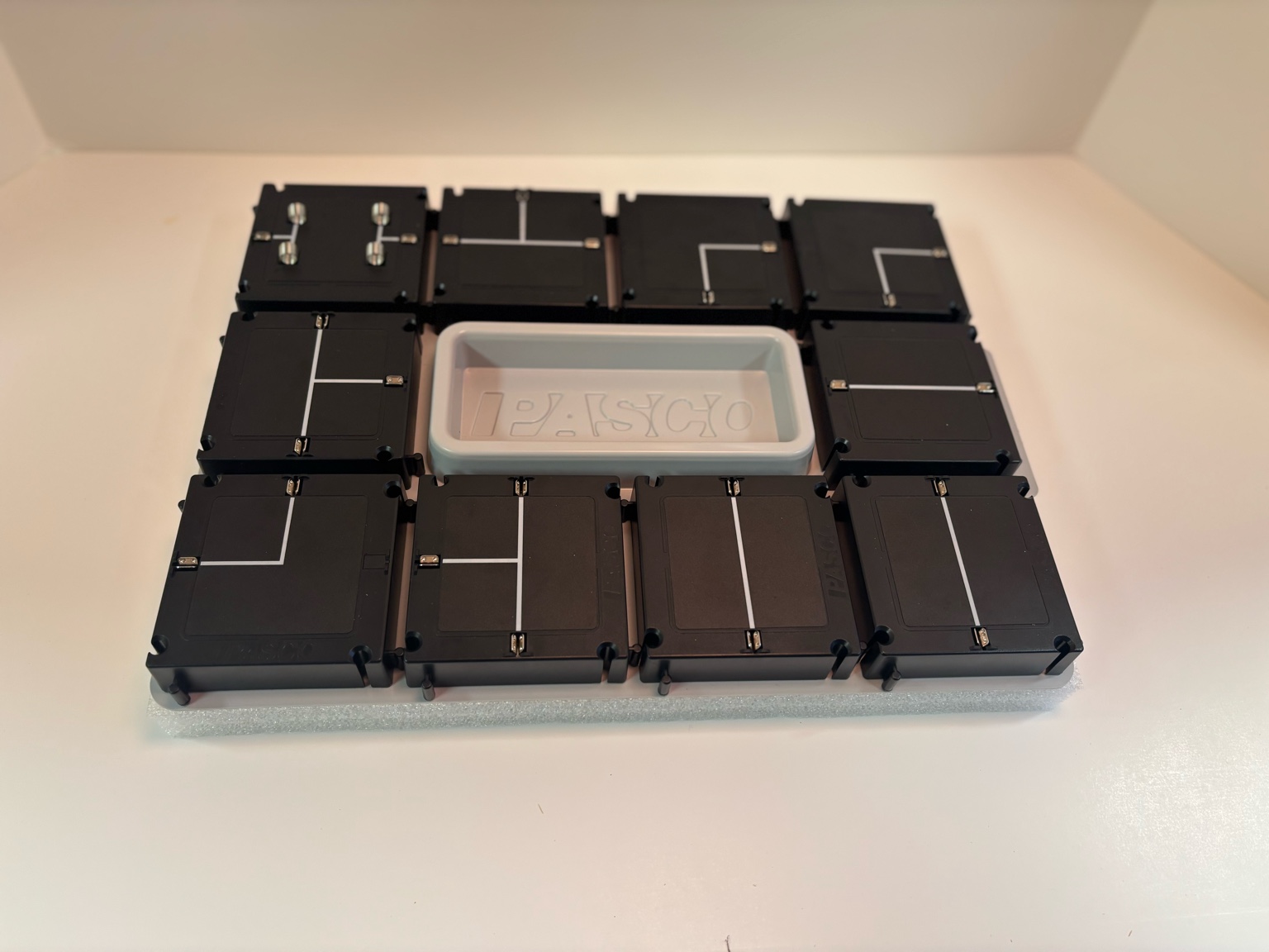 The PASCO Modular Circuit Kit components laid out on a table, including battery, switch, bulb, and connectors, ready for building circuits.