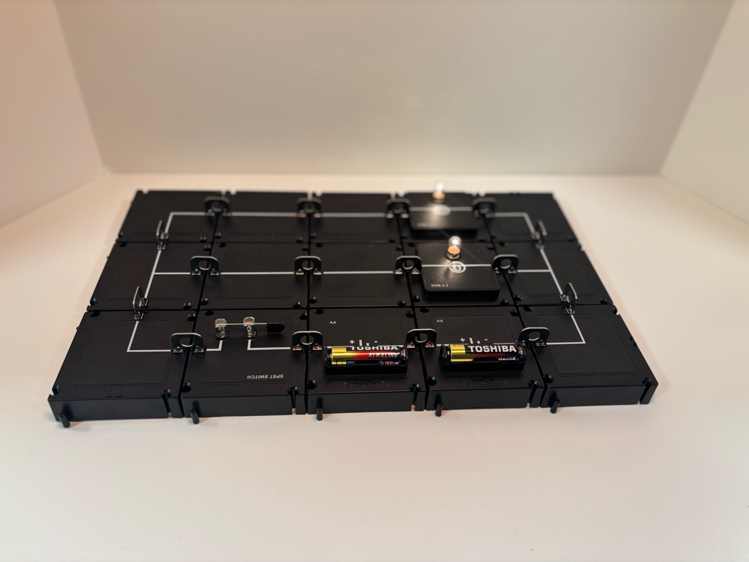 A simple closed circuit built with the PASCO Modular Circuit Kit, including a battery, switch, and light bulb. The glowing bulb shows that electricity flows when the circuit is complete.