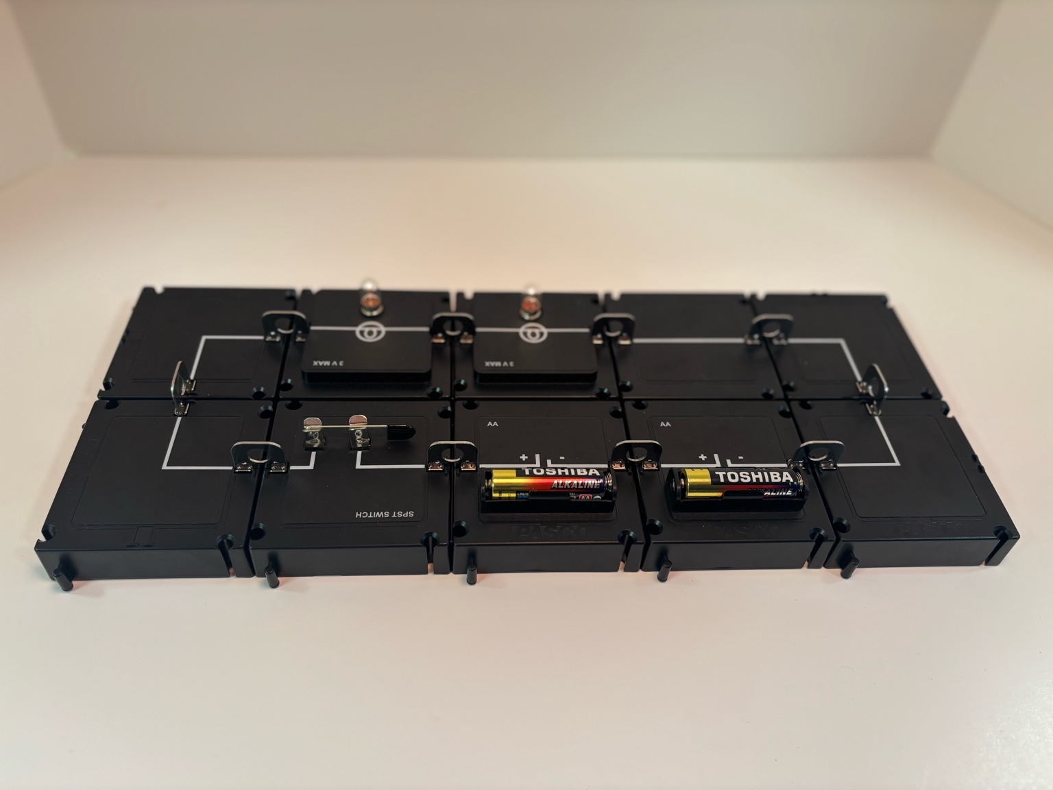 A simple closed circuit built with the PASCO Modular Circuit Kit, including a battery, switch, and light bulb. The glowing bulb shows that electricity flows when the circuit is complete.