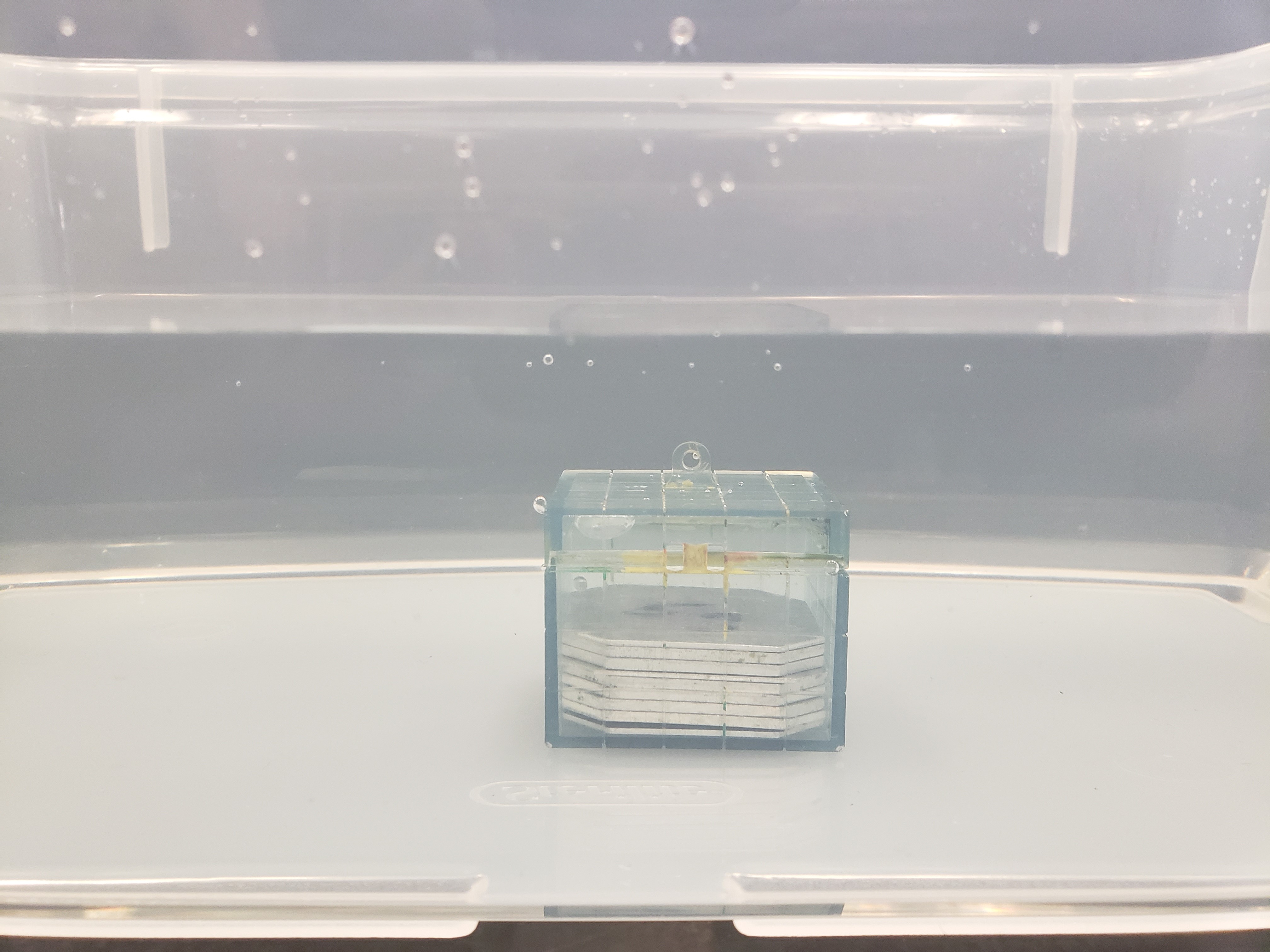 archimedes block filled with weight which has sunk to the bottom of the water-filled container