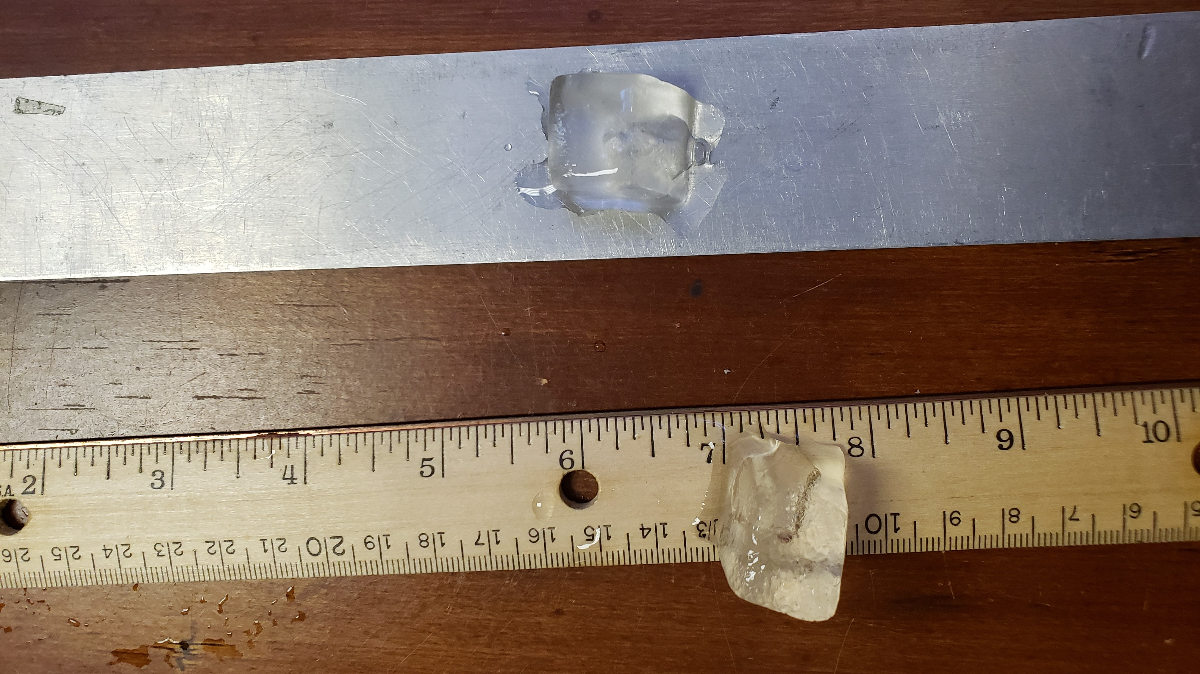one ice cube melting on a metal ruler and one ice cube melting on a wooden ruler