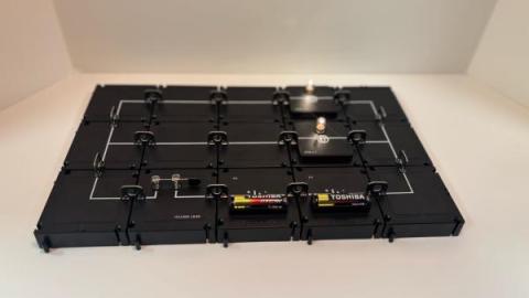 A simple closed circuit built with the PASCO Modular Circuit Kit, including a battery, switch, and light bulb. The glowing bulb shows that electricity flows when the circuit is complete.
