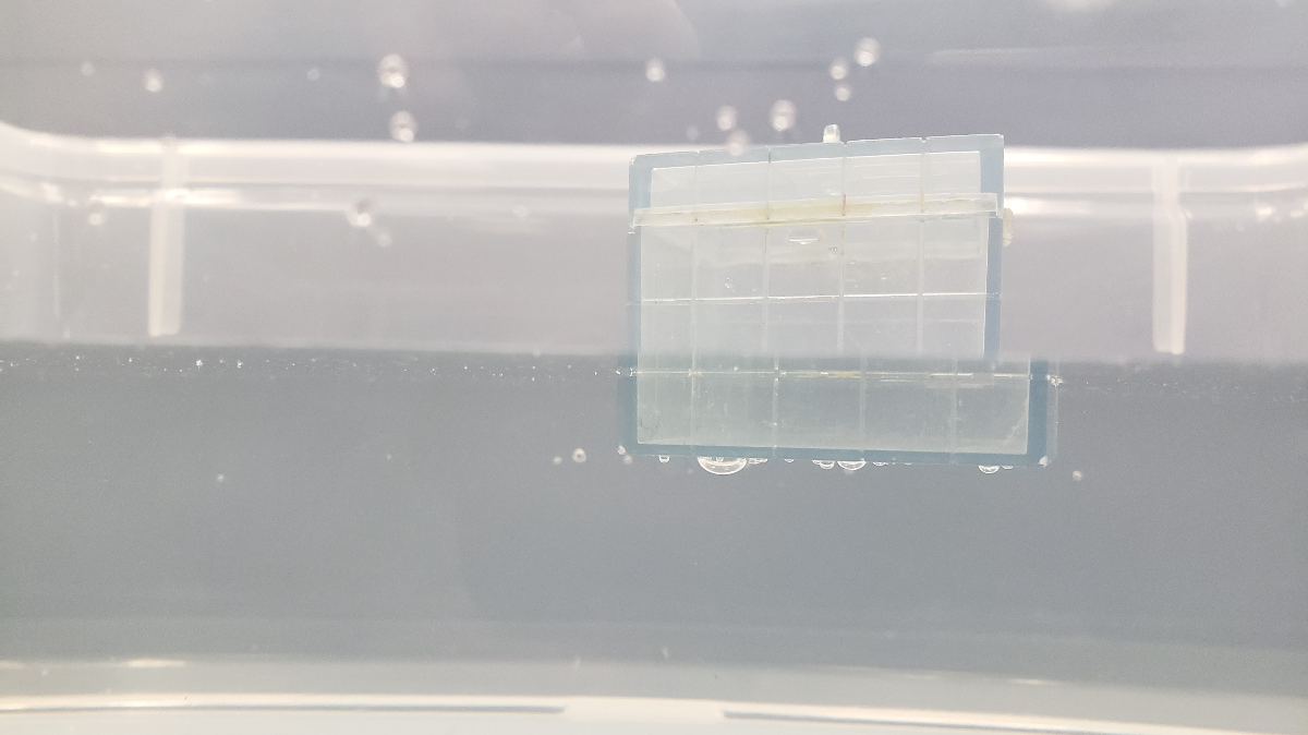transparent block with silver rectangular weights inside partially submerged under the water