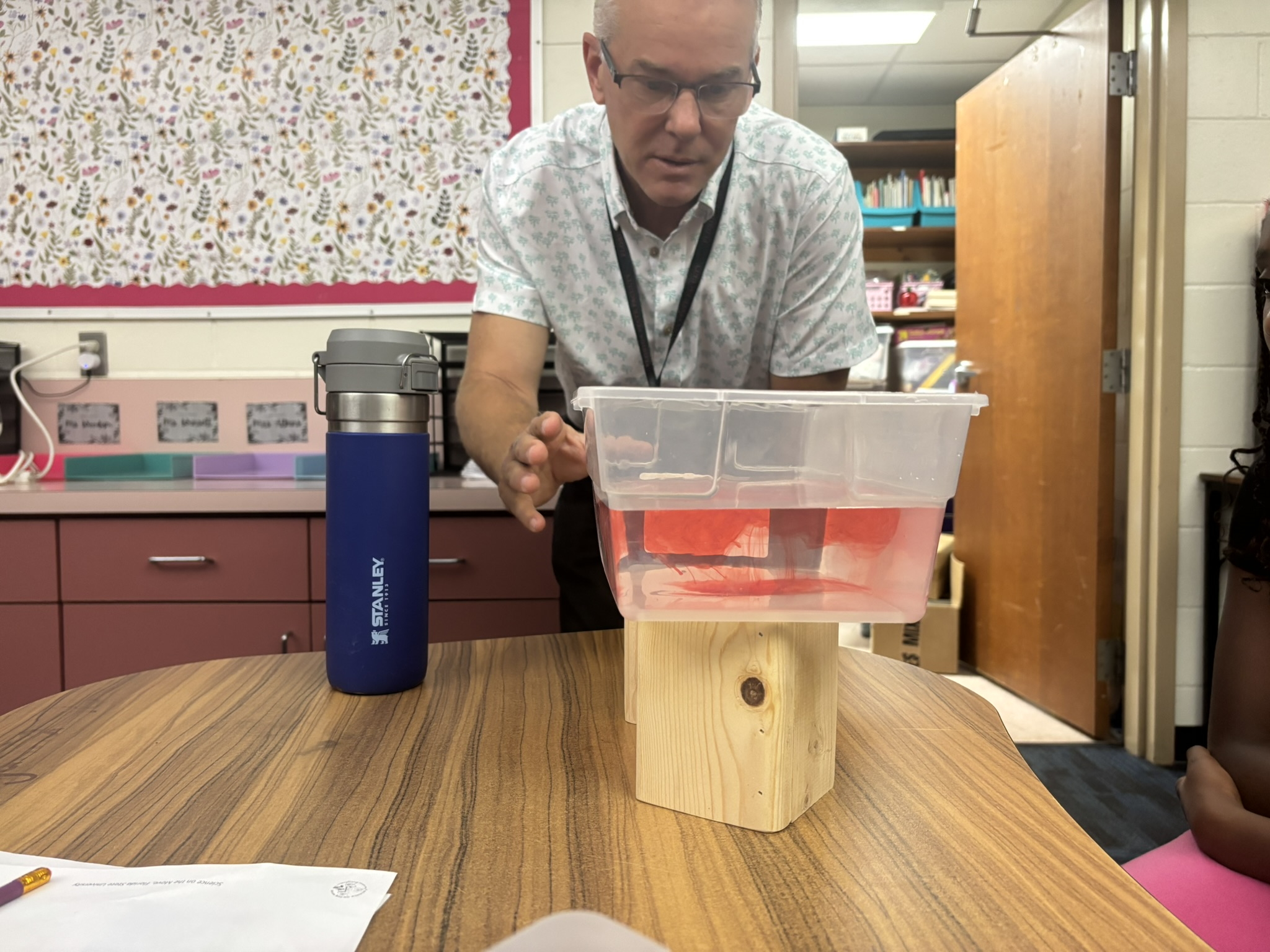 Instructor demonstrating a hands-on science experiment with liquids at a classroom table