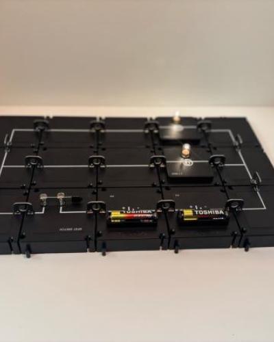 A simple closed circuit built with the PASCO Modular Circuit Kit, including a battery, switch, and light bulb. The glowing bulb shows that electricity flows when the circuit is complete.